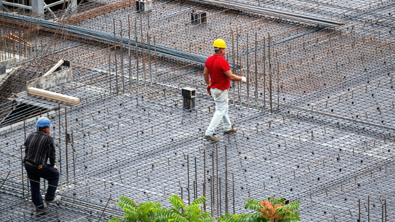 Operários sobre malha de aço em obra de construção civil